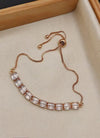 Rose gold bracelet with clear crystals on a beige surface