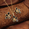 Flower-shaped jewelry set with gold and black details on a brown textured surface