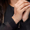 Person wearing a delicate bracelet with small beads on a dark background