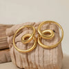 Gold hoop earrings on a textured beige surface