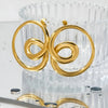 Gold spiral earrings on a textured white surface