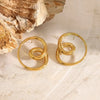 Gold spiral earrings on a textured beige surface with a stone background