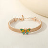 Gold bracelet with a colorful butterfly charm on a light background