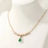 Gold necklace with a green gemstone pendant on a mannequin.