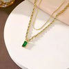 Gold necklace with a green gemstone pendant on a white surface