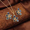 Floral jewelry set with blue flowers and gold accents on a textured brown surface