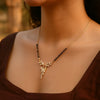 Necklace with a leaf-shaped pendant worn by a person against a blurred background