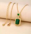 Gold necklace with a green gemstone pendant on a beige background