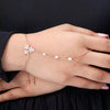 Hand wearing a delicate bracelet with floral designs on a dark background