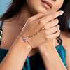 Close-up of a person wearing a delicate bracelet with floral designs on a blue background
