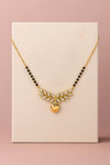 Decorative necklace with black beads and gold heart pendant on a pink background