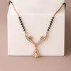 Rose gold necklace with black beads on a white box against a beige background