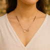 Necklace with a heart and flower pendant worn by a person in a blurred outdoor setting