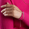 Hand wearing a bracelet on a pink textured background