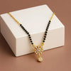 Gold necklace with black beads and a decorative pendant on a white box.