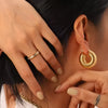 Bold ribbed gold hoop earrings on model showcasing stylish statement jewelry look

