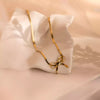 Gold necklace with a bow pendant on a white cushion against a soft pink background
