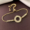 Gold bracelet with circular design and small stones on a brown fabric background