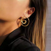 Close-up of a person wearing a gold spiral earring with a blurred background