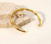 Bamboo-inspired gold bangle resting on stone surface, highlighting texture and natural design