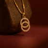 Gold necklace with a circular pendant on a textured brown surface