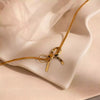 Gold necklace with a bow pendant on a soft beige fabric background