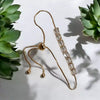 Gold bracelet with crystal-like beads on a white background with green plants