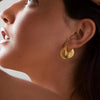 Woman wearing bold gold textured hoop earrings – stylish statement fashion jewelry