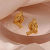 Close-up of textured gold knot stud earrings on satin – modern minimalist jewelry for women
